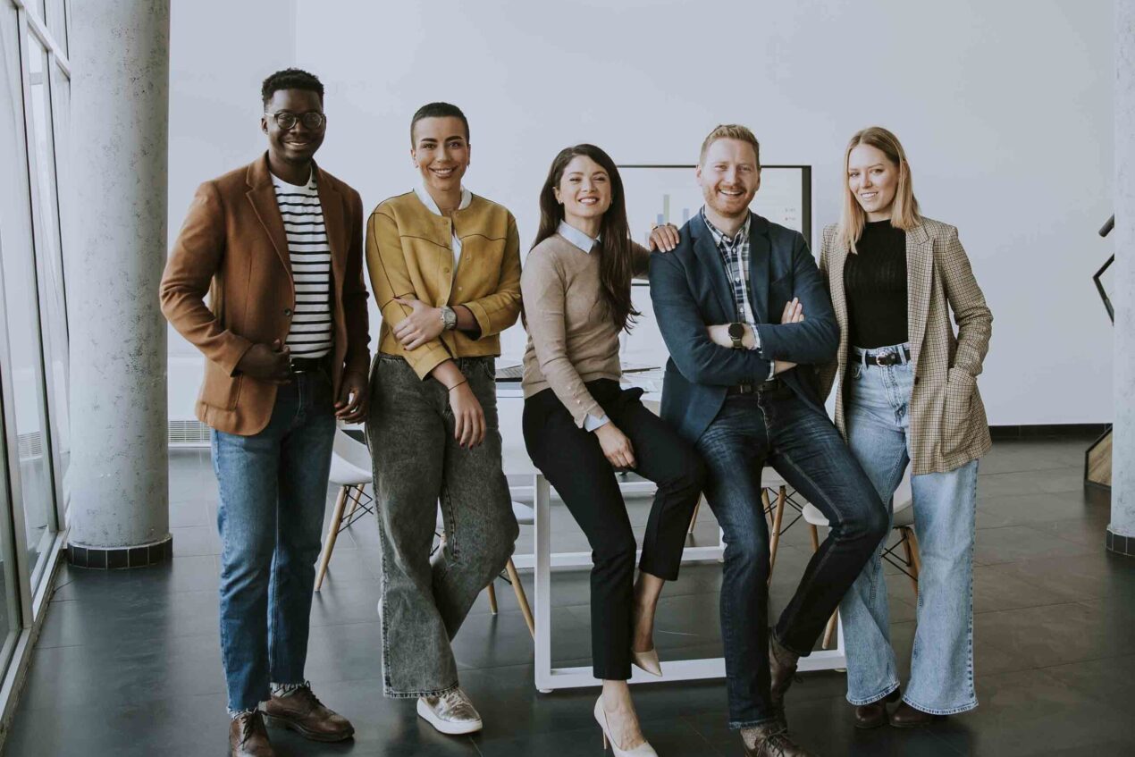 Group of young positive businesspeople standing together in the office